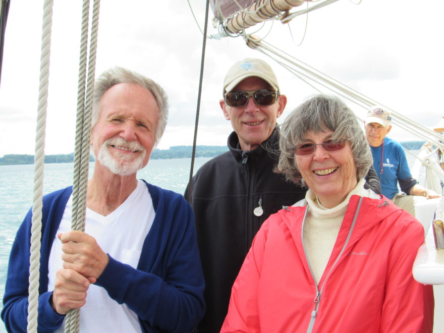 Three adults, one holding the ship's halyards, on a charter sail