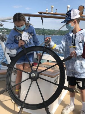 Youth steering ship with large tall ship wheel