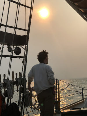 man standing on bow of boat looking out at water